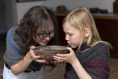 To barneskoleelever lukter på krydder i spiskammerset i Eidsvollsbygningen