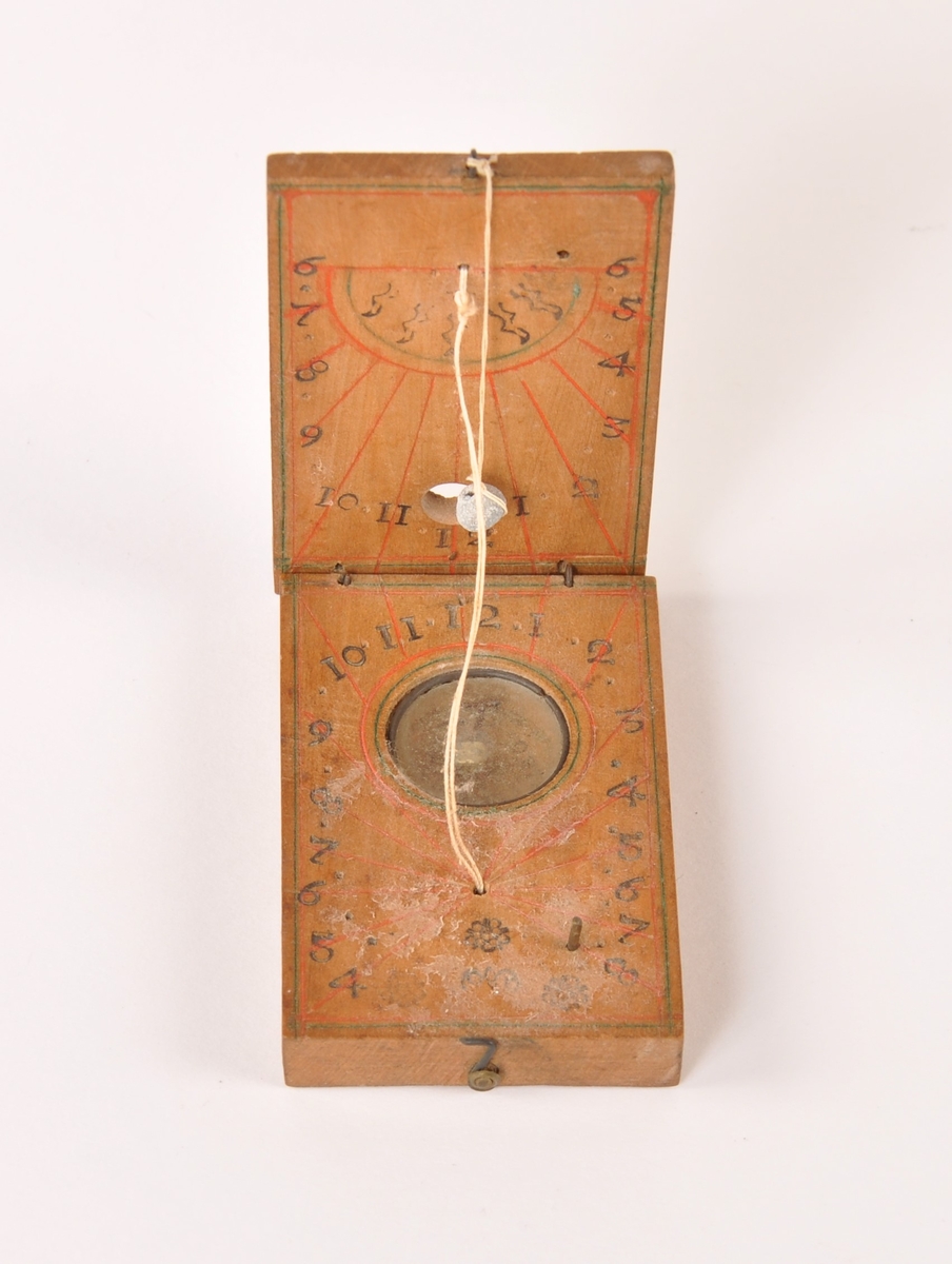 Solur med kompass i lommeformat, laget i tre, glass og metall. Tråd med blyperle viser tiden, påmalte streker for klokkeslett.