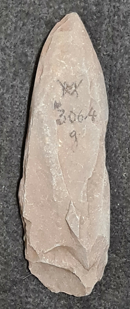 03 064:a-g: Fynd från grusvackarna vid Nols station, Romelanda, Bohuslän köpt av Blomqvist för 15 kr.

a   Kärnyxor, 9 st. De flesta med oregelbunden genomskärning men en med tresidig. allmänhet väl formad egg. L. 12 cm, br. 4 cm.
b   Kärnyxa, delvis avslagen. Eggpartiet bevarat. L. 6 cm, br. 2 cm.
c   Skivyxor, 4 st av ljusgrå flinta. Grovt tillhuggna smalsidor. Fina eggar . L. 6,5 cm, br. 3 cm.
d   Skivyxa av grå flinta. Mycket platt med väl tillknackade smalsidor. L. 9 cm, br. 4 cm.
e   Skivskrapor av flinta, 2 st.
f   Flintavslag med bearbetning.
g   Mejsel av skiffer. Vittrad. L. 12 cm, br. 3,5 cm.