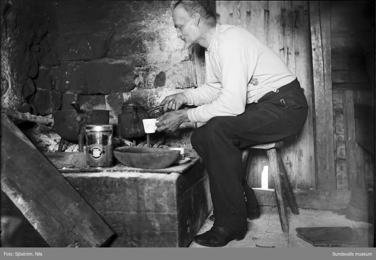 Fotografen Nils Sjöström kokar kaffe på en öppen häll i en stuga på Högön, Juniskär.