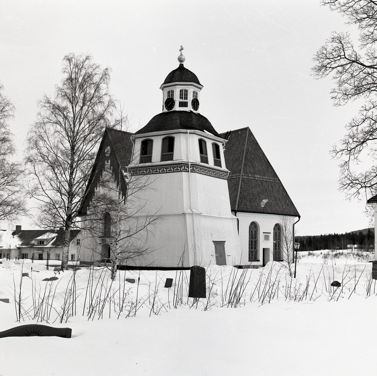 Arbrå stenkyrka, klocktorn och kyrkogård i snö.
