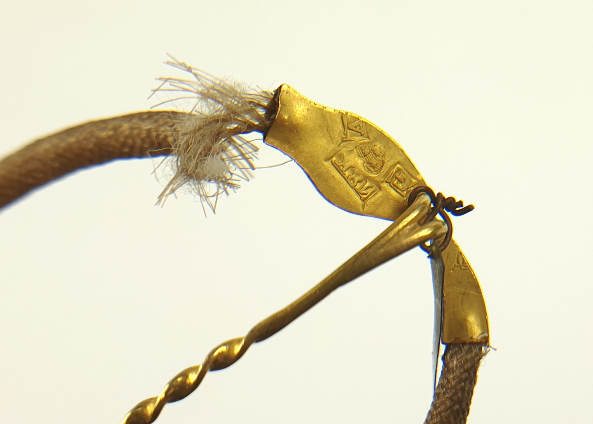 Prydnadsnål, nål av guld. Tillverkad av Arvid Öhrn, Gävle.
Hårarbete: form av en orm. Huvud och stjärt av guld, likaså nålen. Stämplad G 18K m.m.