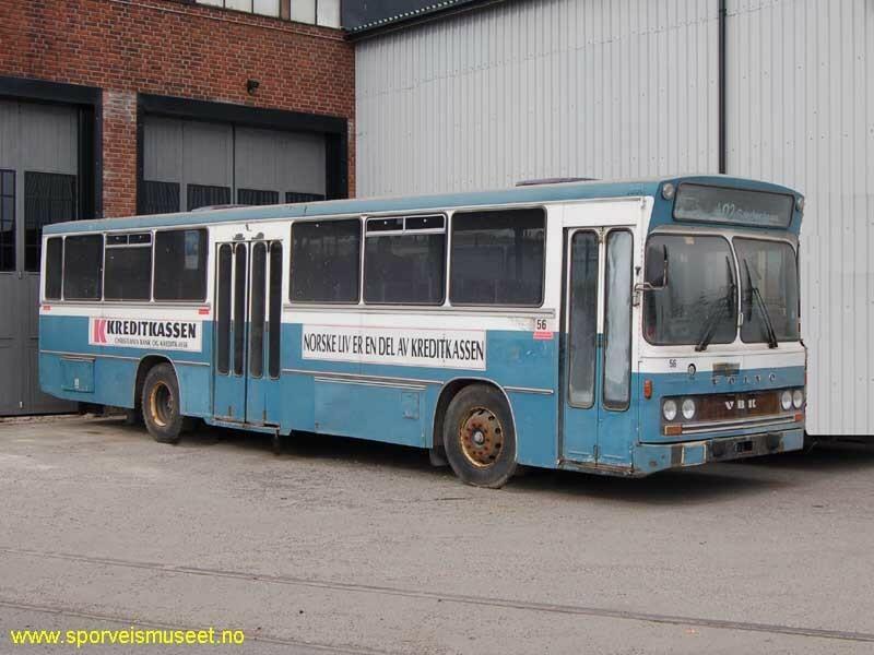 Buss i lys blå farge med hvite partier over dører og under vinduer. I front er det en enkel dør, mens i midten en dobbeltdør. 