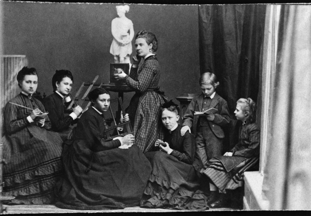 Fotoateljé. Interiör från fotografen Rosalie Sjömans ateljé. Fem kvinnor uppställda vid bl a kameror och retuscheringsverktyg.  En pojke läser i en bok en flicka sitter bredvid.