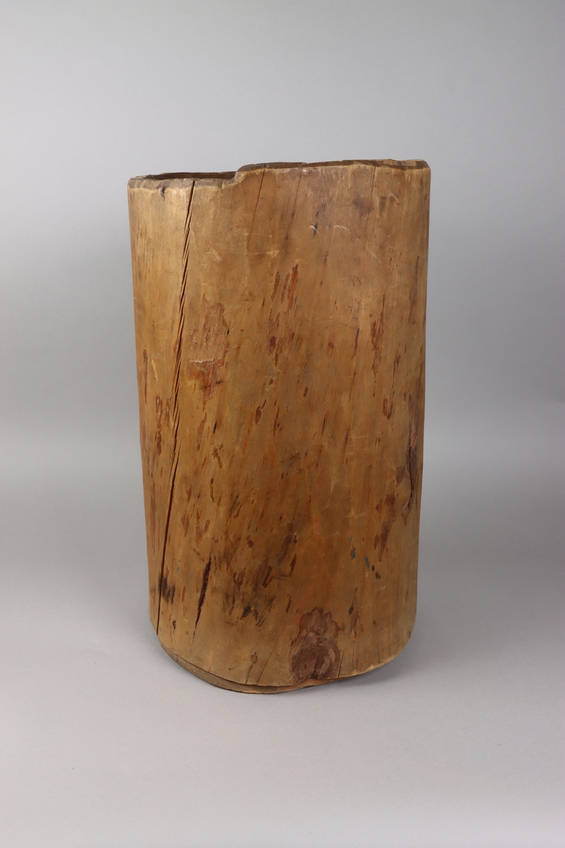 A wooden barrel, carved from the trunk of the tree, below a flat cylindrical end attached with dowels up on the sides of the vessel.