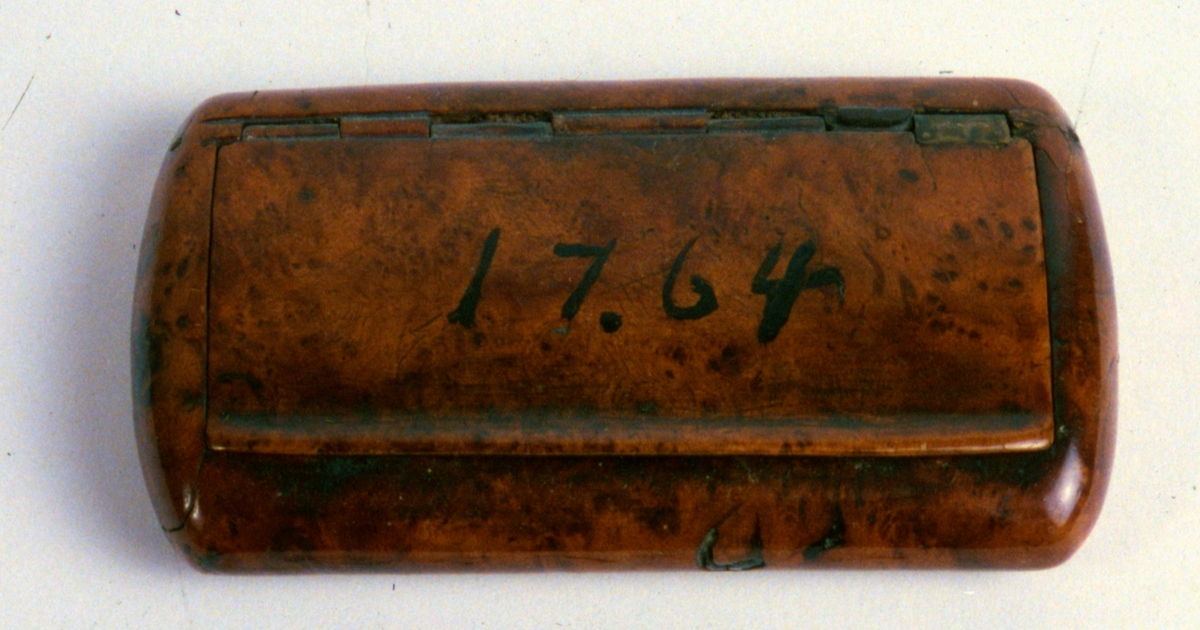 Snusdosa, av polerad masurbjörk, rektangulär med oval genomskärning. Daterad 1764.