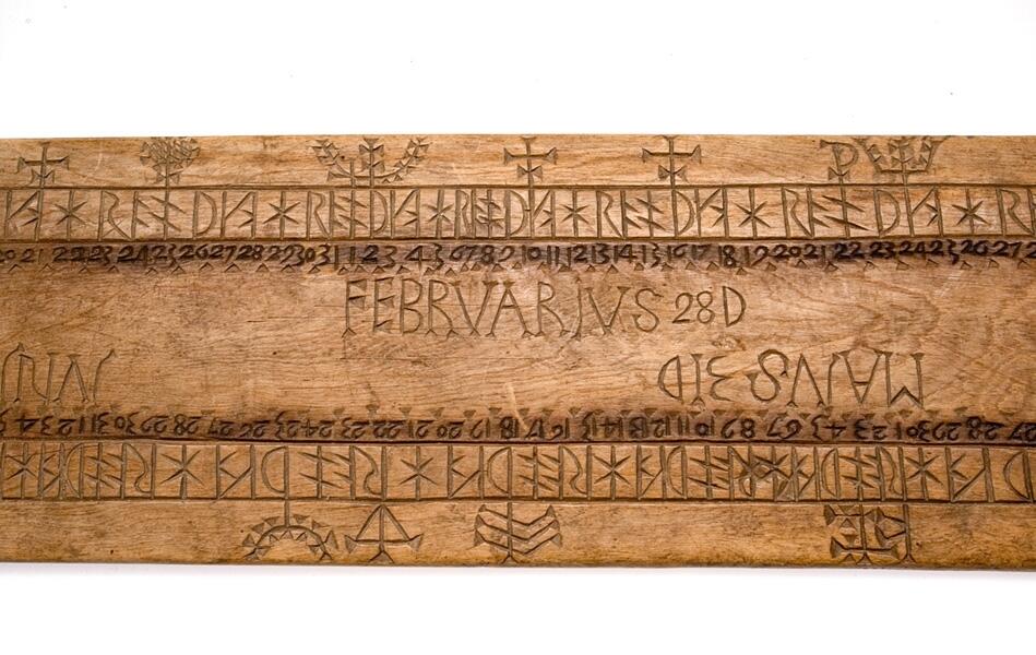 Platt bräde med runt hål vid ena ändan. Något modernare form. Månadernas namn är utsatta och vid varje runa står motsvarande datumsiffra.