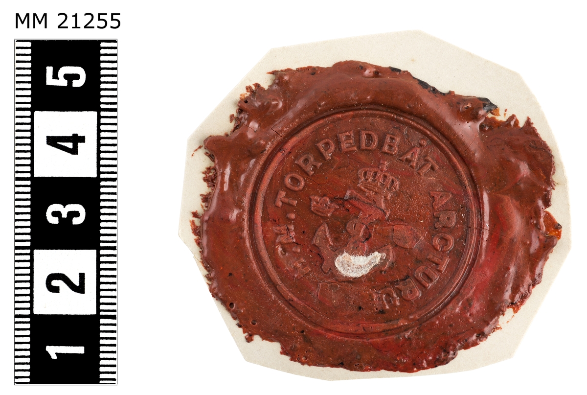 Sigillavtryck av rött lack på papper. I mitten krönt stockankare omgivet av tre kronor. Längs kanten text: "H.M. Torpedbåt Arcturus".