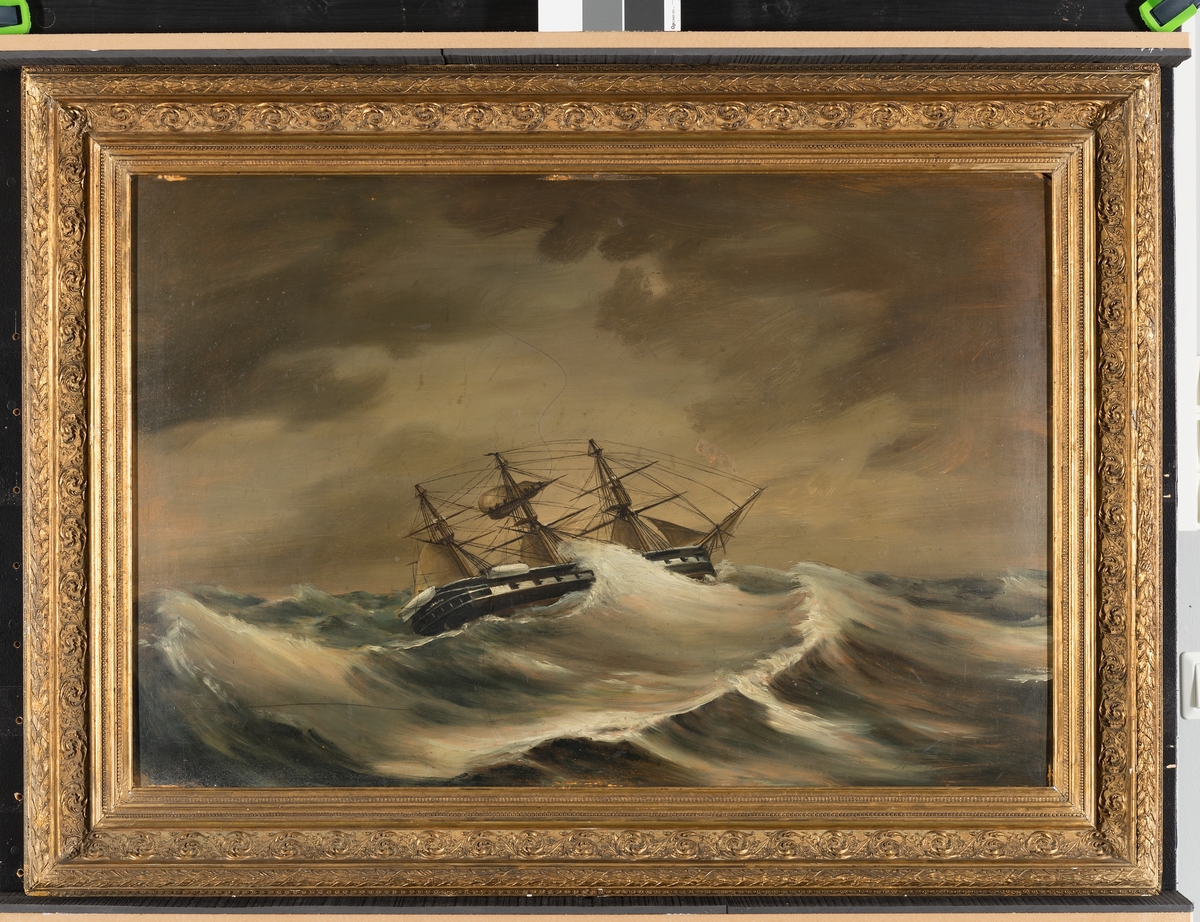 Oljemålning på papp av fregatten Vanadis till sjöss under storm.
Ramen av trä med ornament i förgylld gips.
Målad efter skiss af J. Hägg.