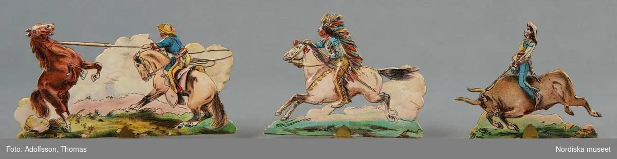 Pappersleksak i flera delar (18 lösa bitar enligt katalogkort) föreställande kamp mellan indianer och cowboys i vilda västern.
