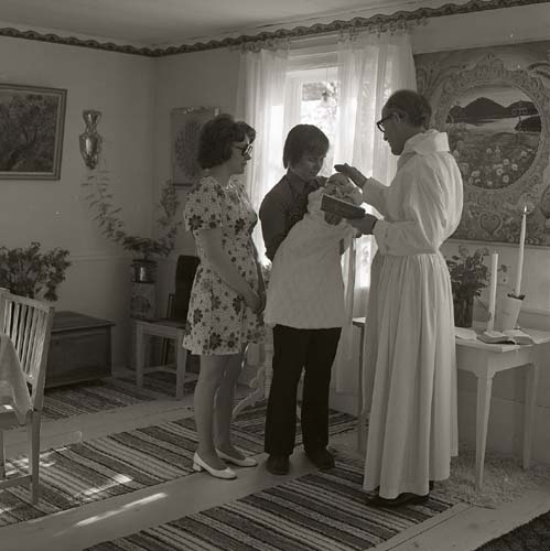 Lill-Annas dop sommaren 1973, här i ett rum på gården Sunnanåker. Föräldrarna står med barnet vid prästen som välsignar det.