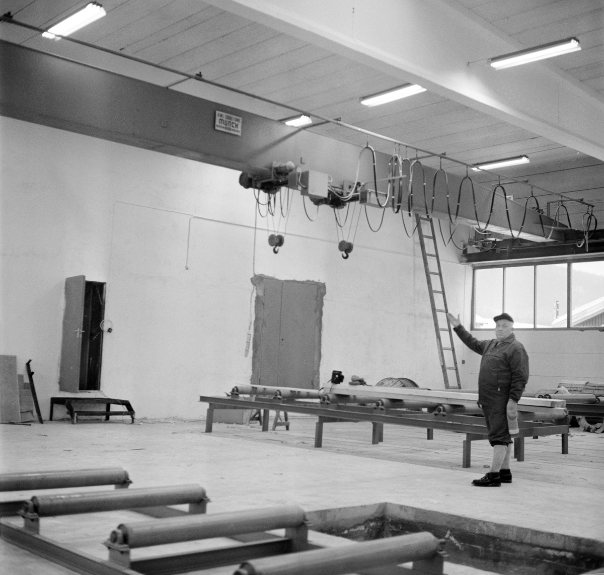Disponenten ved Trysil kommunale sag og høvleri, Jostein Bjørnersen (1916-1998), fotografert mens han viste rundt i de nye produksjonslokalene bedriften fikk bygd i 1970-71. Mer informasjon om dette moderniseringsprosjektet finnes under fanen «Opplysninger».