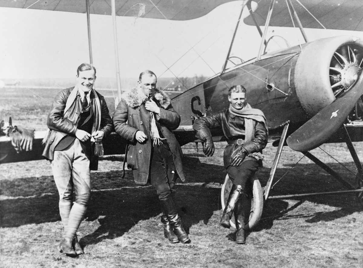 Tre män står framför flygplan Thulin LA med hjulställ i Ljungbyhed, 1920.