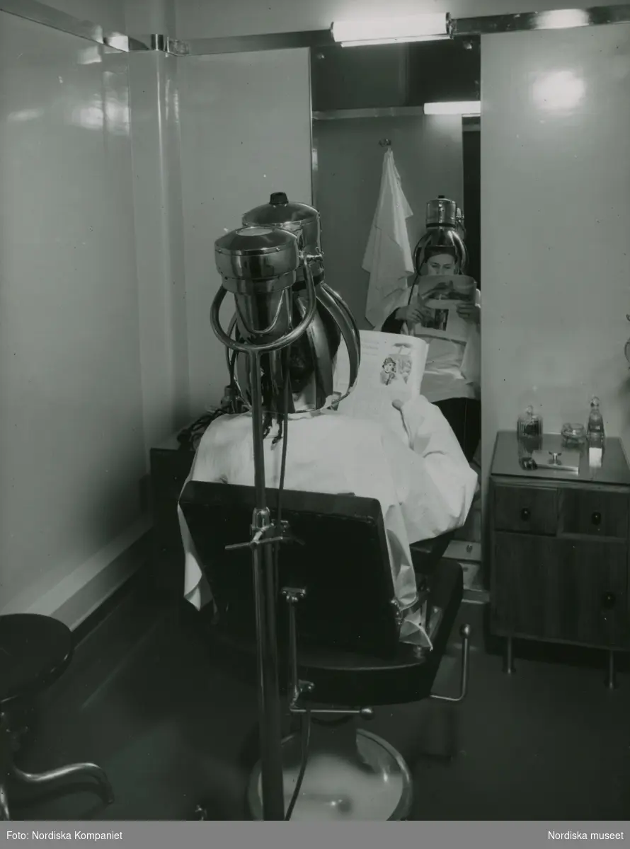kvinna med huvudet under en torkhuv. Nordiska Kompaniet. Text med blyerts på baksidan: "Hygieniska avd. Jan. 1935 torkhuv".