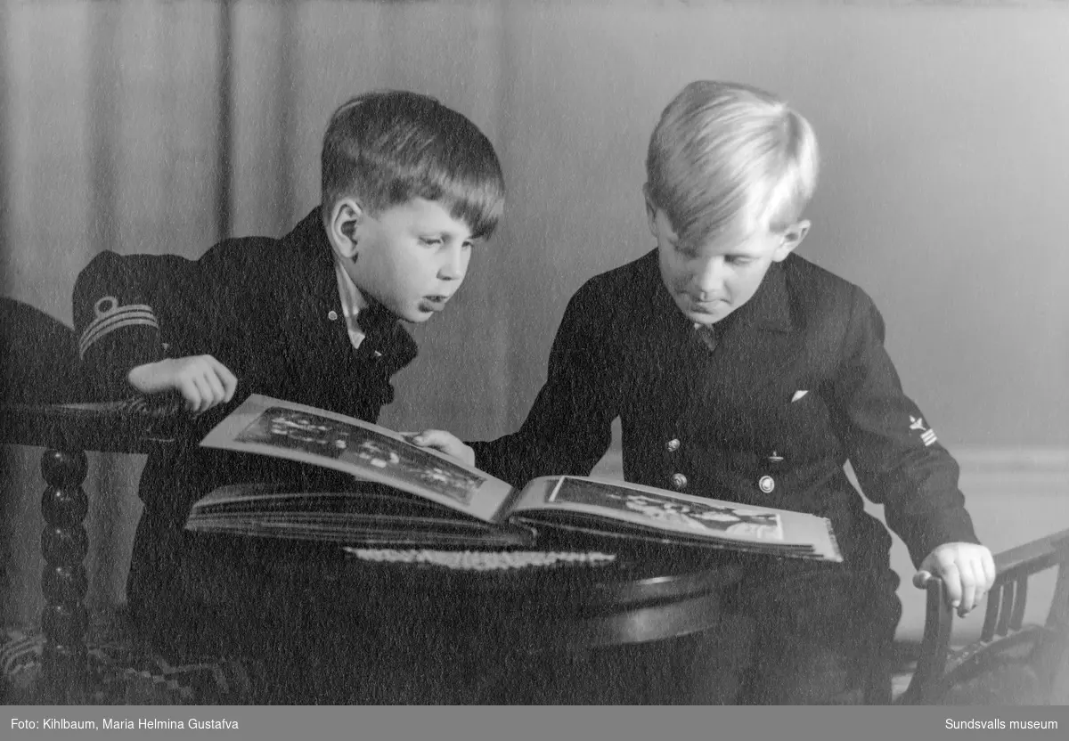 Två pojkar tittar i ett fotoalbum.