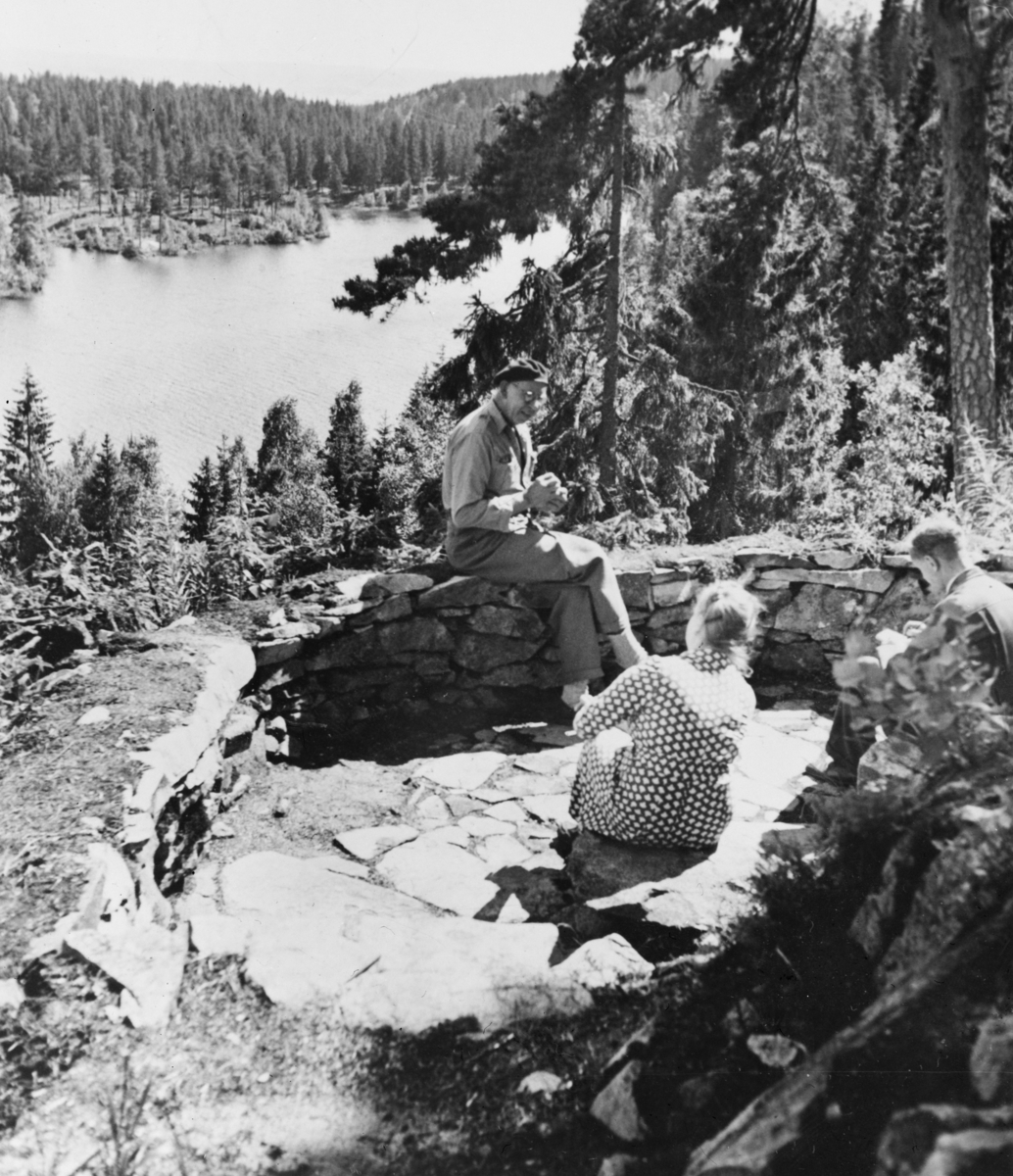 Reprofoto av gruppebilde med landskap i bakgrunnen. Avfotografert etter ukjent original. Årstallet 1949 står skrevet på fotografiet.