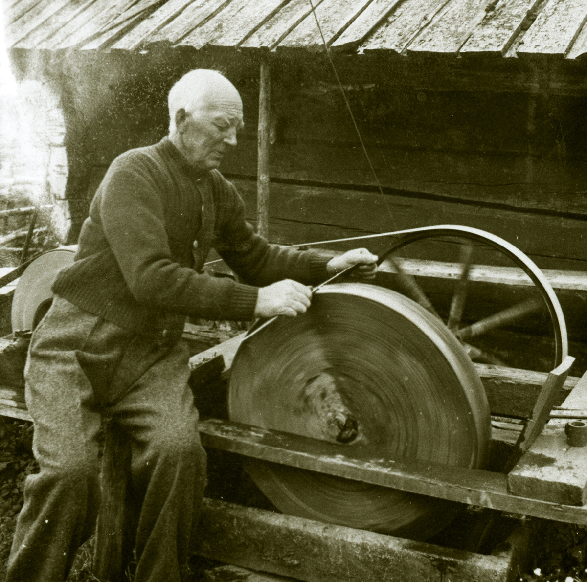John Remmen sliper ljåen. Slipestein-sveiva er bytt ut i eletrisk motorkraft, for straumen kom i 1940.