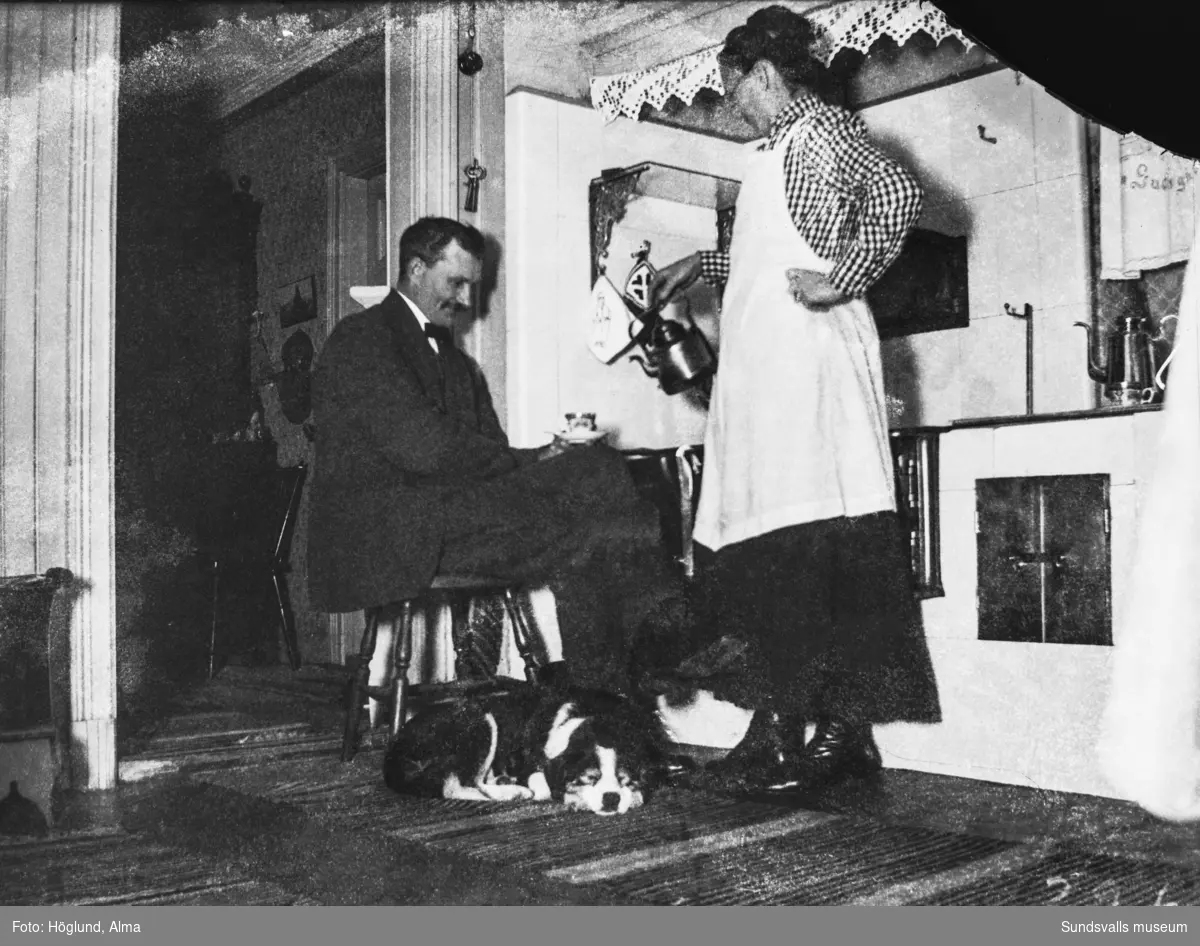 Emil och Sanna Eriksson framför vedspisen i köket i Råvlan, Stöde. Hunden Piff har rullat ihop sig på trasmattan vid spisvärmen.