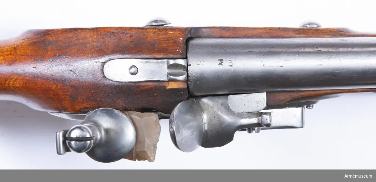 Gevär med flintlås, reparationsmodell 1815.
Låset märkt "CS", pipan märkt "AT PG S". Pipor från div äldre svenska gevär, som ändrats till likhet med 1815 års pipor. Lås från diverse äldre svenska och utländska gevär, som om så behövdes försetts med varhake. I övrigt som 1815 års gevär.