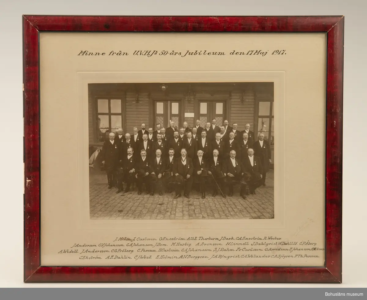 Ramat och glasat fotografiskt bild i svartvitt med texten "Minne från U V H J.s 50 års Jubileum den 17 Maj 1917" som avbildar UWHJ, Uddevalla -  Vänersborg -  Herrljunga järnvägsaktiebolags styrelseledamöter taget vid 1917 års 50-årsjubileum till minne av av bolagets första tågresa 1867. 
Ingår i en serie porträtt med ram av trä med namn i präglad mässingsplåt. 
Ledamöterna i  bokstavsordning:
1) John Bark
2) O. H. Bergqvist
3) N. O. Bruce
4) F. Carlsson
5)  C. W. Colliander
6)  H. B. Hegardt
7)  David Jacobowsky
8)  N. T. V. Linnell
9) C. F. J. d’Orchimont
10) C. O. S Posse
11)  Karl Rasmussen
12) E. Sparre
13) R. M. Thorburn
14)  W. F. Thorburn
15) Minne från U V H J.s 50 års Jubileum den 17 Maj 1917.

Ur handskrivna katalogen 1957-1958:
Femton fotografier U.V.H.J.
14 foton av styrelseledamöter 1863-1940. 
1 foto av (styrelsen?) vid 50-årsjubileet 1917. 
Alla inramade.

Lappkatalog: