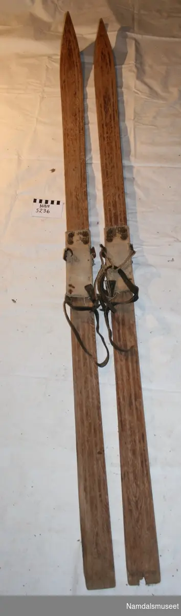 Teknikk: Tjærebredd under og overflatebehandlet. Bindinger av seildukssåle, metallfeste til reimene, taug og lærreim. Innskjært mønstre på skiene.