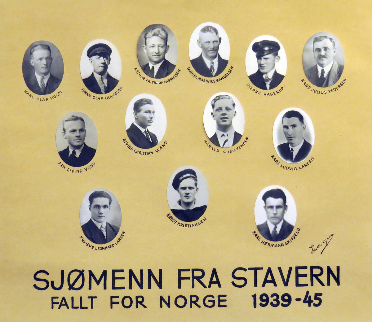 13 sort-hvitt-portretter av unge menn er limt på en gul papp. Det står skrevet: Sjømenn fra Stavern, fallt for Norge 1939-45er limt