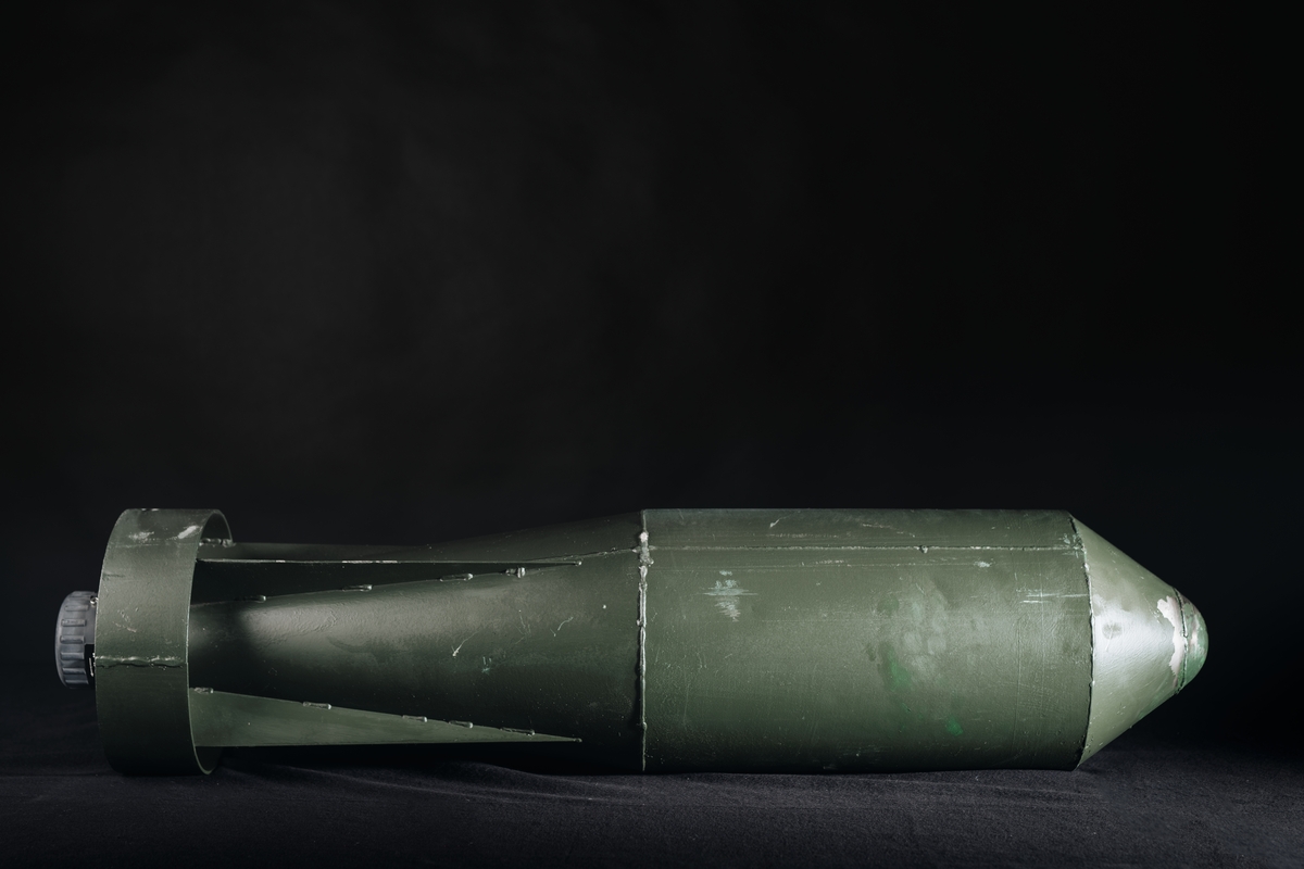 Grönmålad raketliknande sjunkbomb. I bakre änden sitter en Undervattenständare 06 med en graderad vridratt på vilken djup för explosion ställs in.

På en grön klisterremsa finns text: "Blind sjunkbomb 11 m UVT 04".