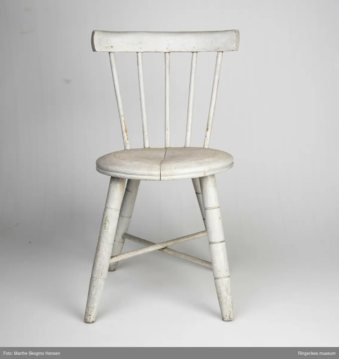 Stolen er veldig pent laget, den ser akkurat ut som en stol for voksne, bortsett fra størrelsen. Det er en typisk pinnestol, med rundt sete. Beina har tre dekorative furer hver, 8,5 cm, 16 cm og 22 cm opp fra gulvet. Det er to sarger i kryss. Ryggen består av 5 pinner på 20.5 cm og et smalt ryggbrett på toppen, 4,5 cm bredt. Stolen er malt lys grå, men fargen er slitt vekk noen steder, av og til ned til den hvite grunningen, andre ganger er det slitt ned til treverket.Det er en sprekk på tvers av setet, men ellers er stolen i god stand.