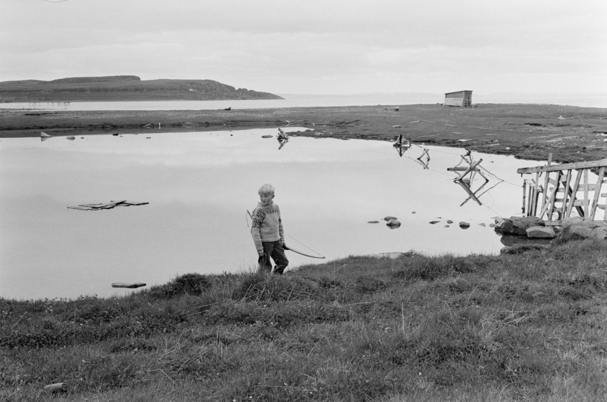 En gutt med pil og bue ved i et kystlandskap