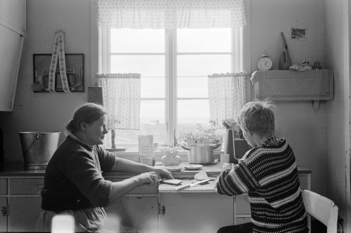 Eldre kvinne og ung gutt spiser ved kjøkkenbenken.