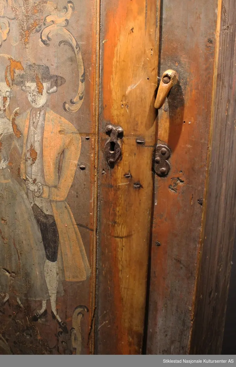 Matskapet dekorert med rosemaling og figurmaling av «rokokkomaleren» Ole Haldosen Berg (1747-1828). 
Gesimsen øverst på sideveggene er fjernet, og spikrene på hengslene er skiftet ut, ellers er skapet intakt med originale beslag (festet på nytt?). Motivet på døra viser et par i finstasen med rokokkoranker rundt. Øverst på døra står bokstavene TES.MJD. Over døra står årstallet 1755, men dette er overskrevet med bokstavene N.O.S.M..E.T.D.M og årstallet 1789. Vi antar at S og D i begge tekstene står for sønn og datter, og at dette er initialene til eierparene, som har skiftet i 1789.
Skapet har en del slitasje på høyre side av døra, ved låsen, etter åpning og lukking av skapet. Etter høyden på disse slitesporene å dømme, har også de minste vært inne i matskapet en del i løpet av årene. Helt nederst vises også hull etter mus som har gnagd seg inn på jakt etter mat. Baksiden av skapet er grovt tilvirket, her vises tydelige spor etter bearbeiding med både øks og pjål/skjøve. Innvendig har skapet tre hyller, mangler nøkkel. Skapet er malt av Ole Haldosen Berg (1747-1828).
