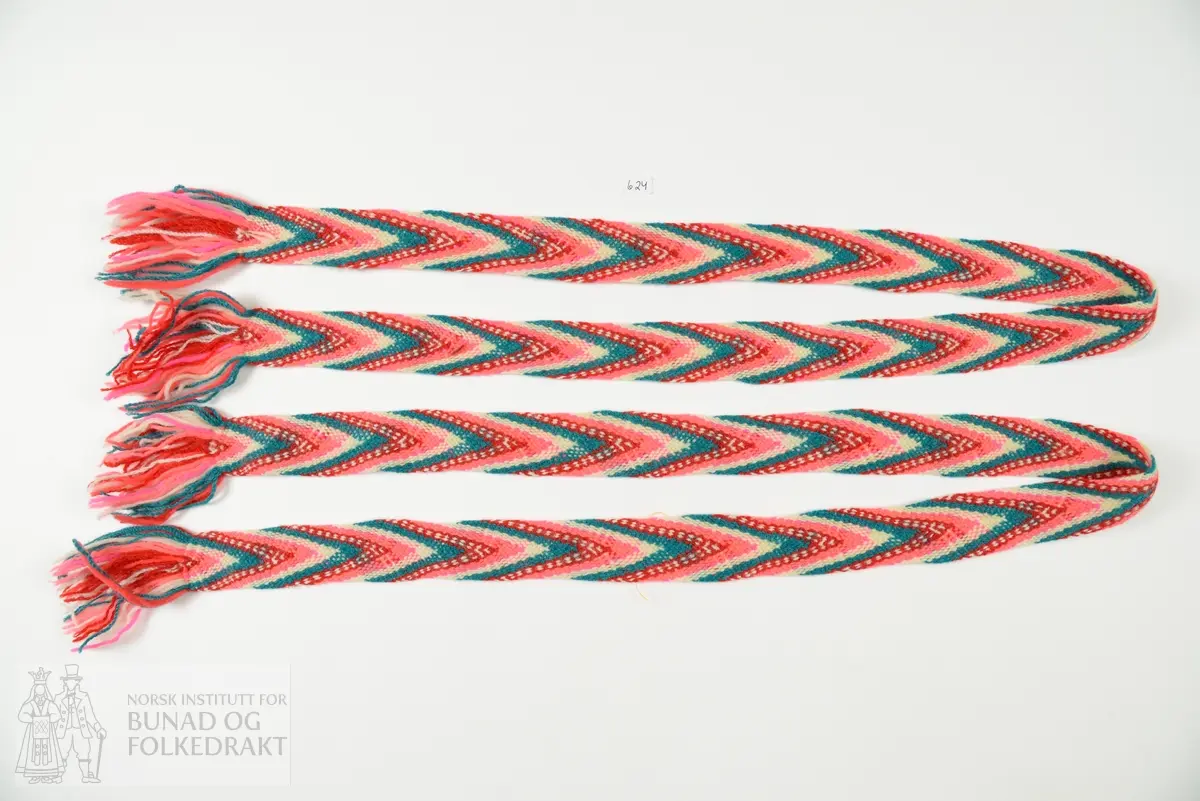 Bånd, Strømpebånd, 2 stk.
Fingra band, i fargene rosa, rødt, hvitt og blågrønt.
Frynser i hver ende.
