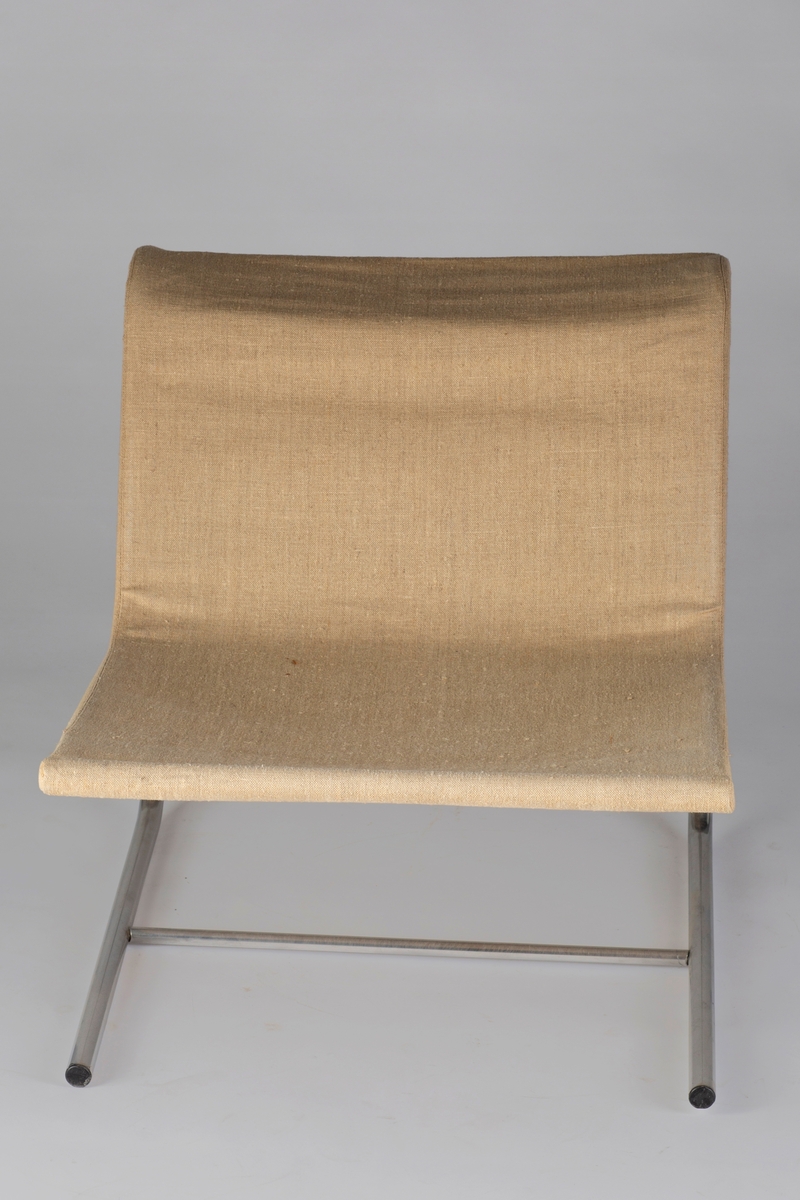 Stol av bøyde stålrør med påtredd trekk av grovt, dobbelt lerret som danner stolens sete og rygg. Løs, rektangulær, flat pute i lys beige bomullsstoff med brune og svarte striper. Puten er delt opp i 7 paneler, som gjør det enkelt å brette den.