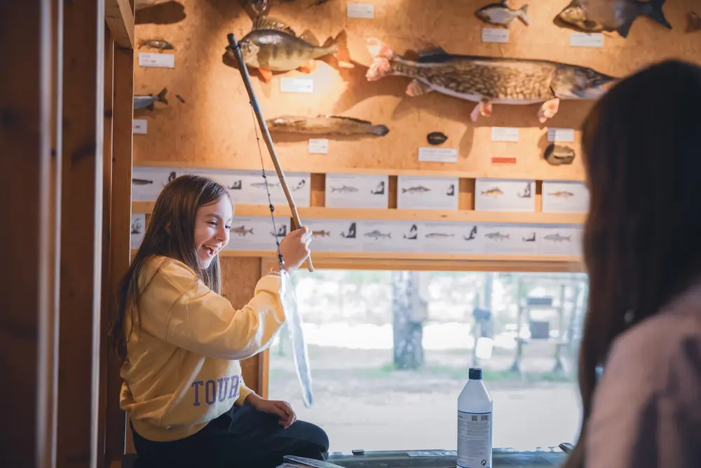 Foto av to barn som fisker etter plastfisker i fiskedammen inne på besøkssenteret