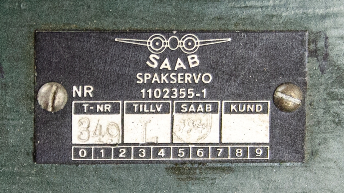 Spakservo, tillhörandes flygplan 32, Lansen. Av metall, oregelbunden form med flera utskjutande delar. Uppskuren för undervisning och monterad på stativ. Tillverkad av SAAB, nummer: 1102355-1.