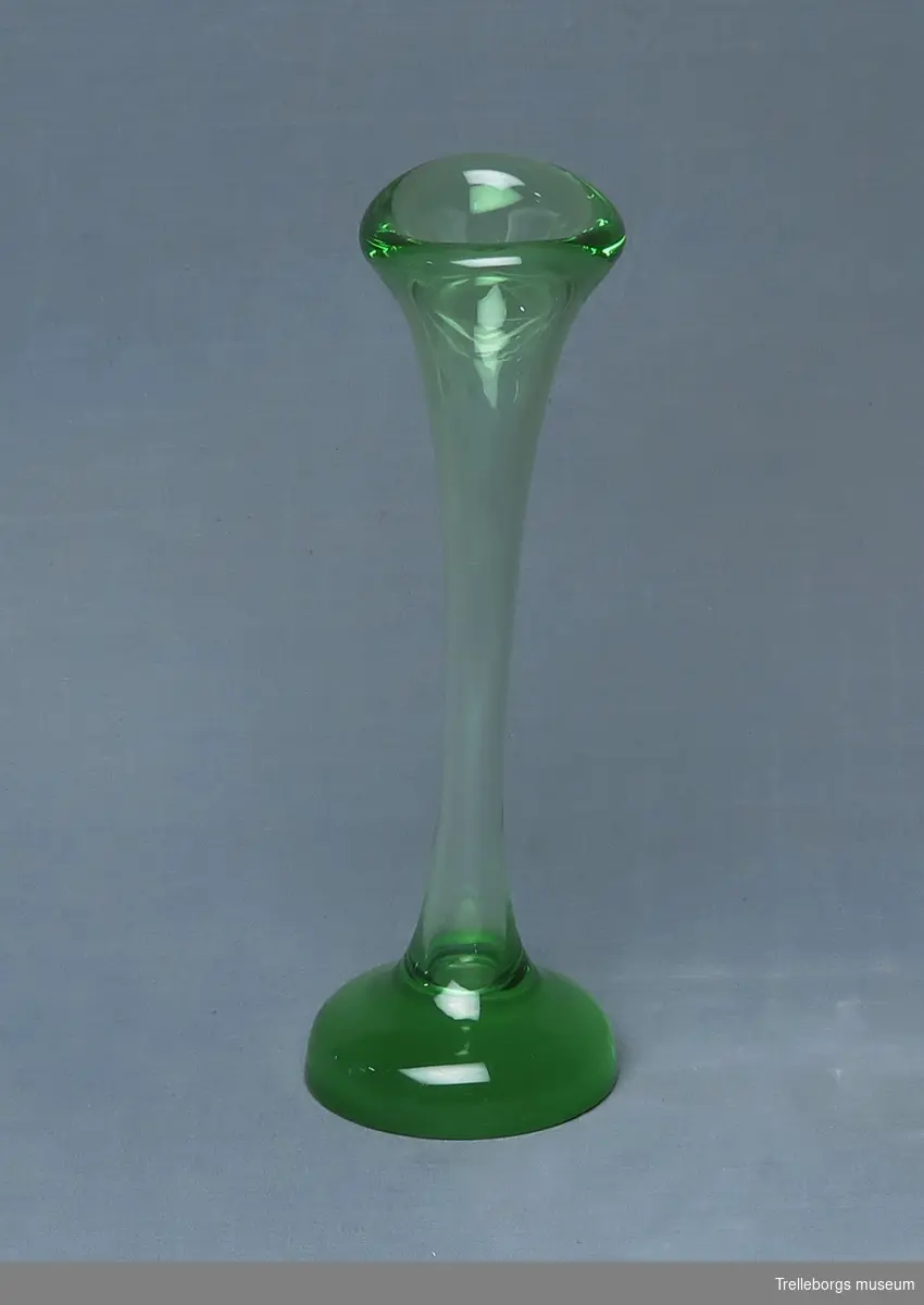 Smal vas i grönfärgat glas. Kraftig fot och mynning. 

Brukar kallas för "hungaben" [hundben].