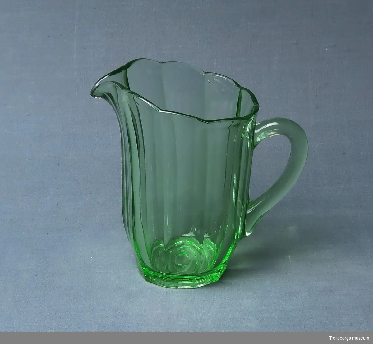 Kanna i grönt glas med vågig kant.
