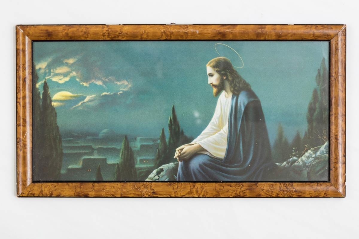 Bilde i glass og ramme. Motivet er Jesus, natur og bygninger bak, Måne som kommer frem bak. Brun treramme, lakket og beiset.