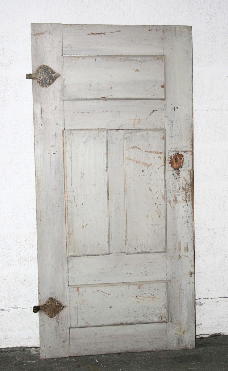 Dörr med 4 speglar, 2 liggande, 2 stående. Ena sidan grå, andra sidan vit. 2 stora lövformade beslag. Lås. Bruks-och färgslitage.

Till dörren hör foder.