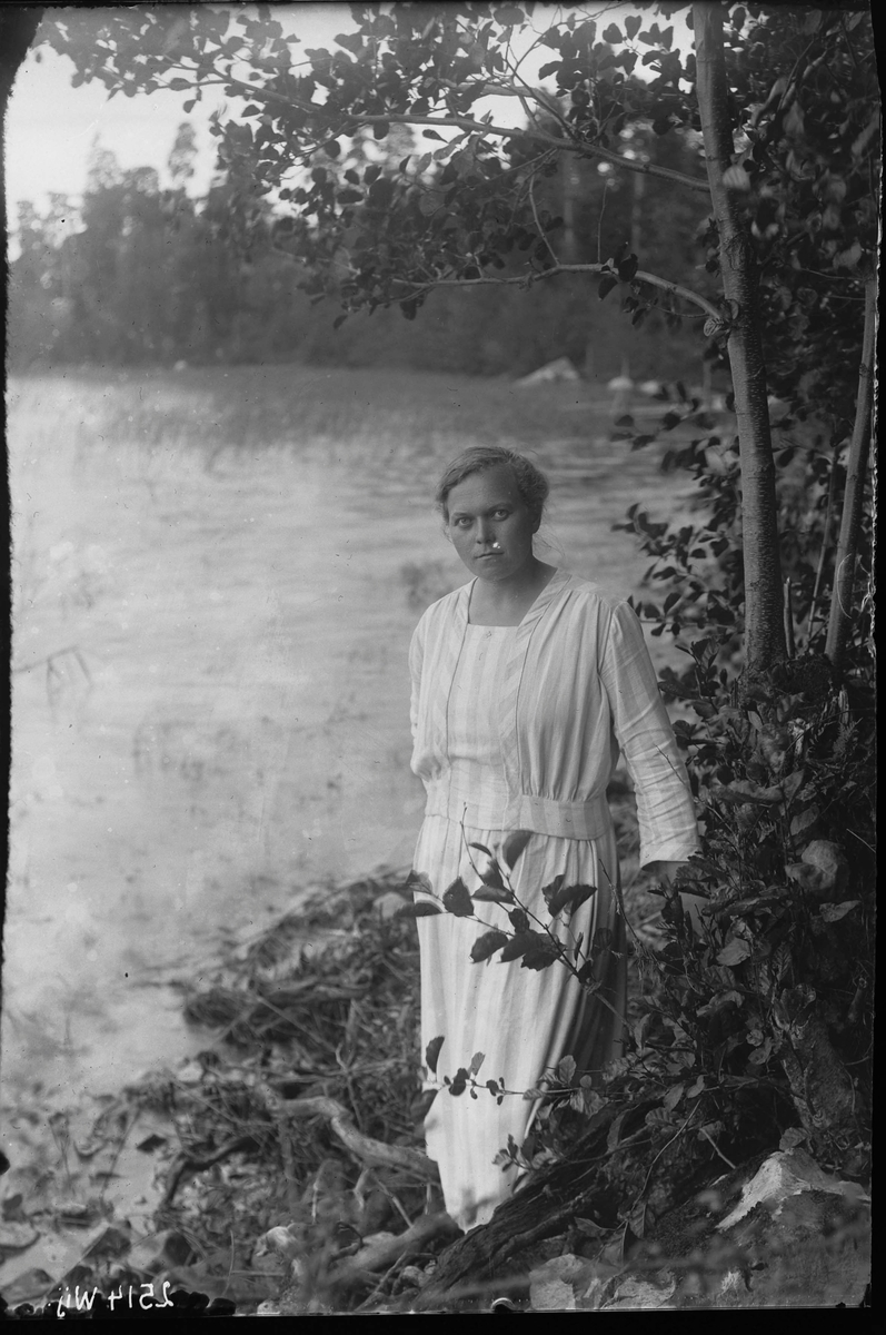 Fotografering beställd av Ringdahl. Föreställer småskolelärarinnan Elsa Margareta Ringdahl, född 1892-11-04 i Västerås, död 1964-04-03 i Västerås. Bosatt på Östermalmsgatan men här avbildad vid vattnet i Frösåker.