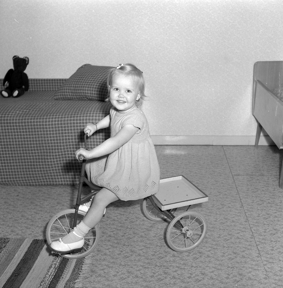 Okänd flicka fotograferad cyklandes på en trehjuling i sitt hem.