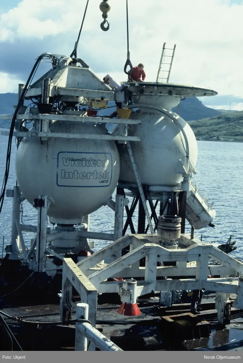 Moduler for et undervannsanlegg heises over kanten fra en båt eller lekter. Det står "Vickers Intertek Limited" på den ene modulen.