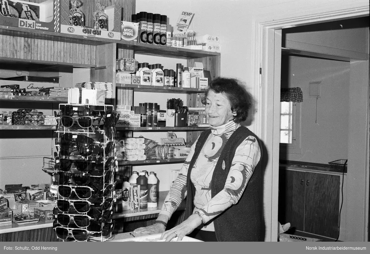 Kvinne bak disken i butikken på Frøystul. Mange varer ligger i hyllene.