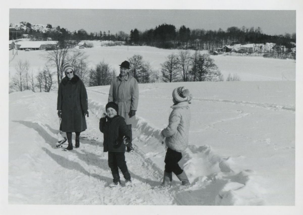 Familjen Edvardsson står i ett snörikt landskap, Labacka mot Långåker cirka 1965. Lilly och Bertil Edvardsson med sonen Ralf (född 1957) och dottern Marianne (född 1953). Till vänster skymtar Långåker 1:2 och till höger Kjellmans stuga.