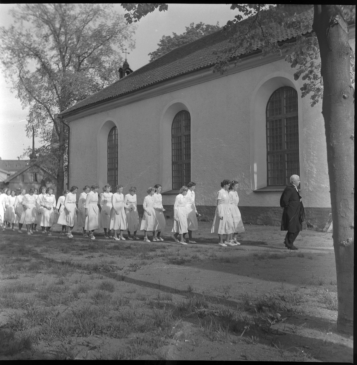 Kvinnliga konfirmander tågar utanför Christine kyrka. maj 1950