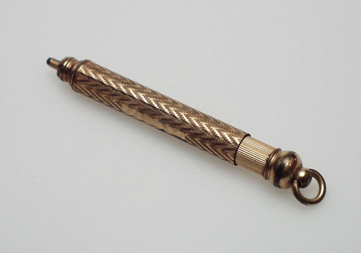 Bronsefarget blyant i metall med sikksakkmønster. Blyanten er uttrekkbar og har hempe.