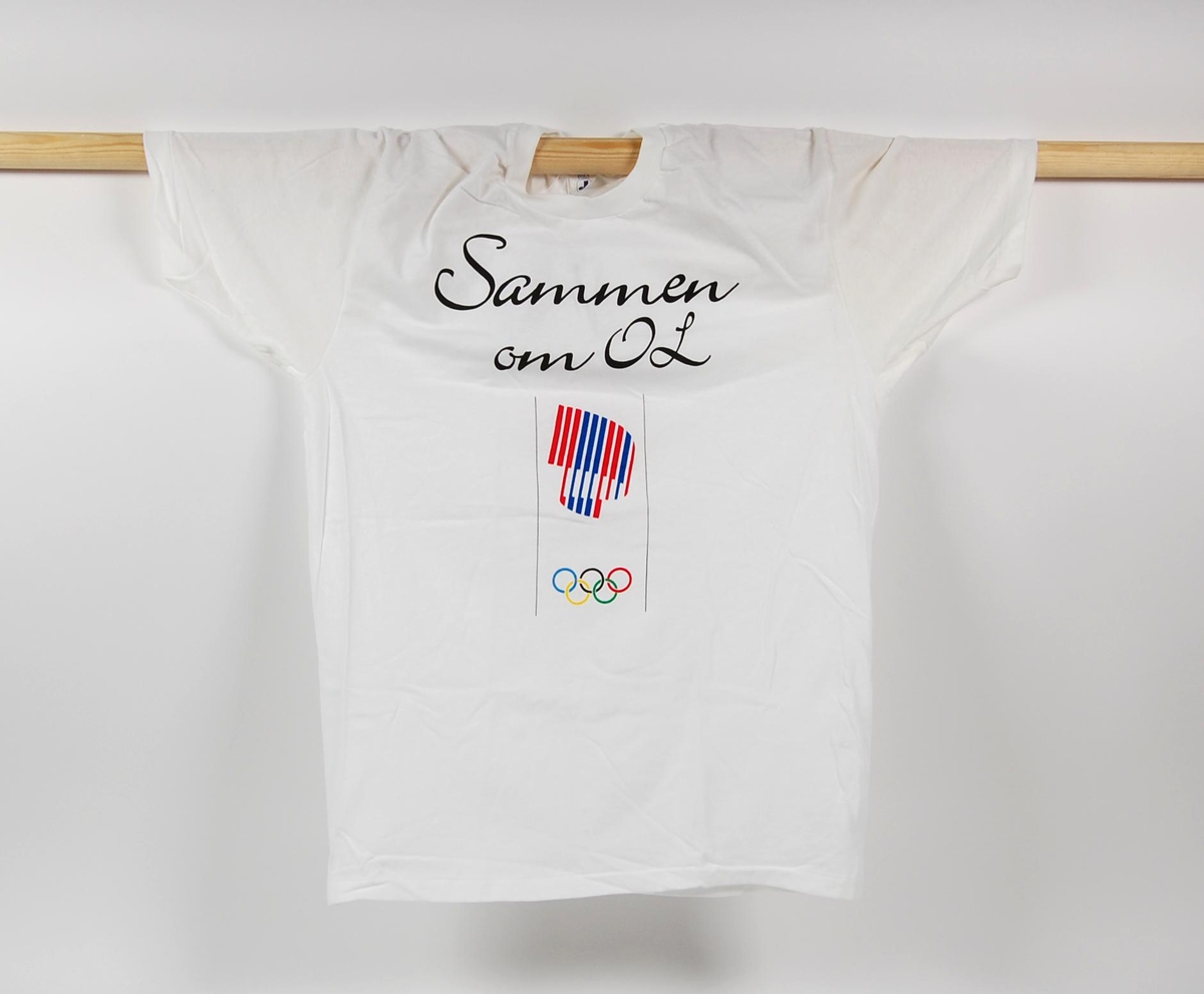 T-skjorte med hvit som hovedfarge. Påskriften "Sammen om OL" på fremsiden. På fremsiden er det også en logo for de olympiske vinterleker på Lillehammer i 1994.
