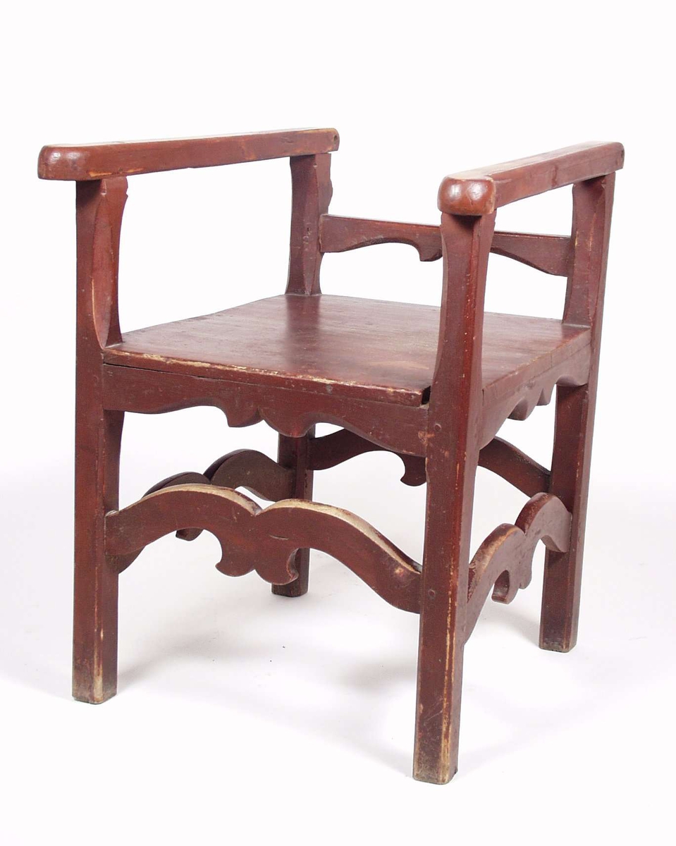 Stolen er av bjørk og er rødmalt med utskjæringer. Stolens rygg mangler. Ryggen har vært hengslet, slik at den kan slås ned som bordplate.