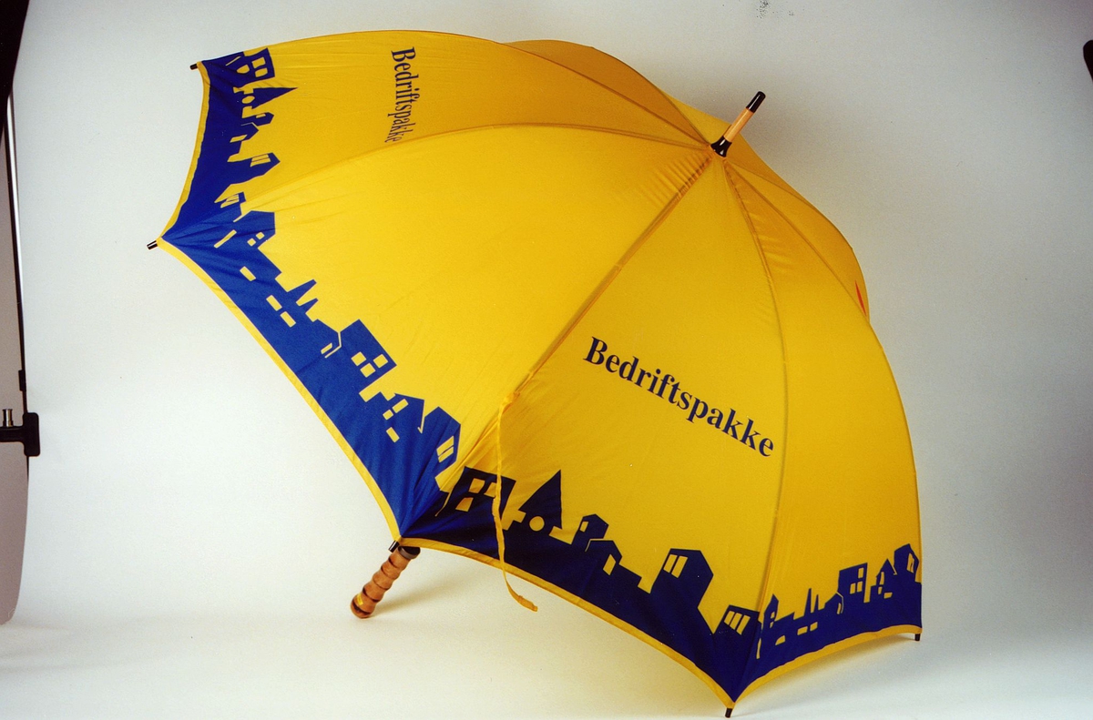 Paraply, gul med blått trykk og rød logo; reklameartikkel fra Posten Lettgods.
Tekst: Bedriftspakke
ex 1
ex 2
Fotografi: PMF.9.0.00321
              PMF.9.0.00322