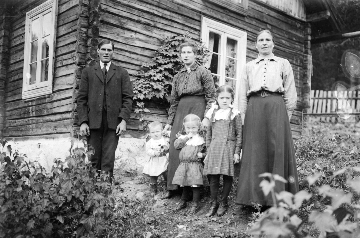 To kvinner, en mann og tre barn foran Fossheim på Fåvang - trolig Ingmar Ånsløkken (nedre) og hustru Anna med barna Ola (fra venstre), Olave og Anne, til høyre Oline Fossheim som er mor til Anna